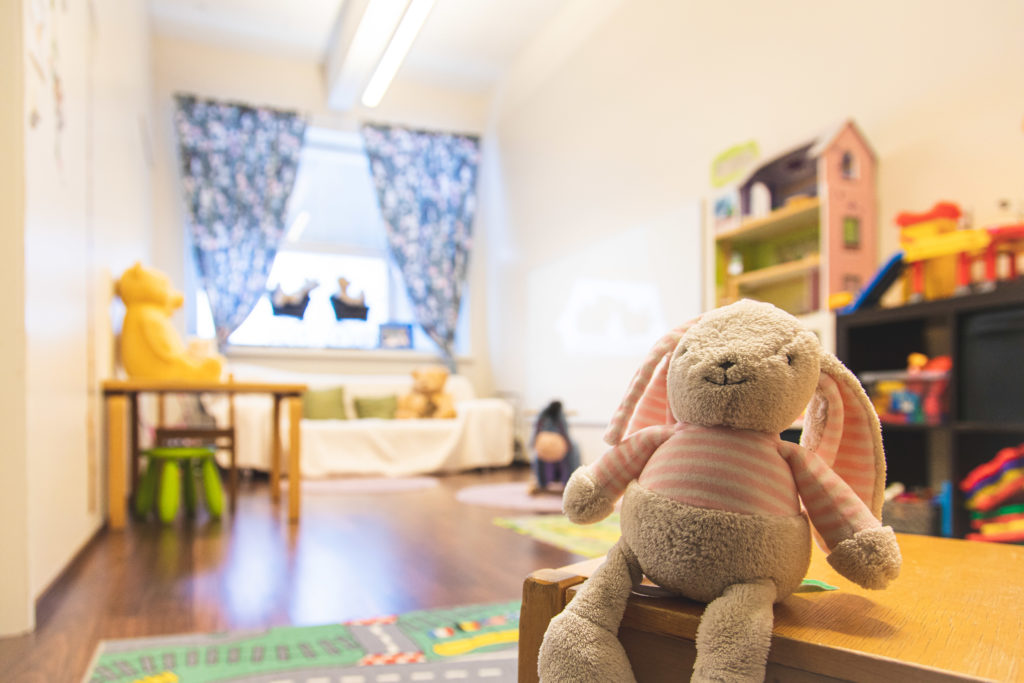 Valoisa lastenhuone, jossa on pehmoleluja sekä nukkekoti