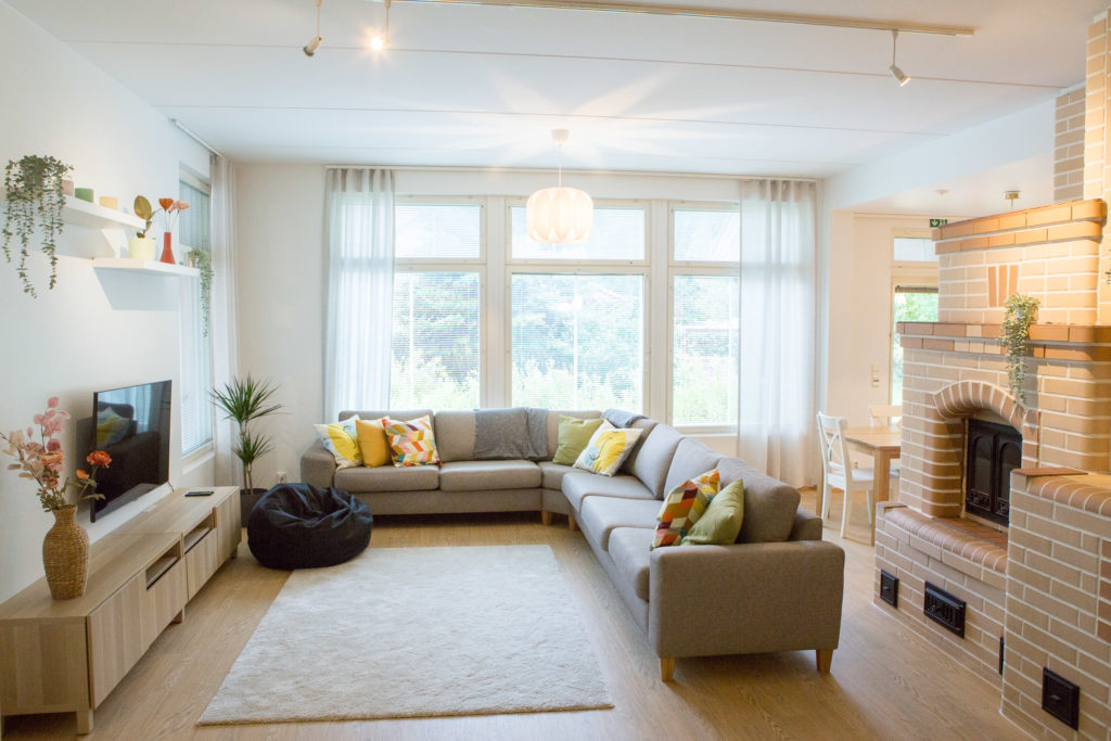Aarnin valoisa olohuone, jossa on TV, mukava sohva ja iso takka