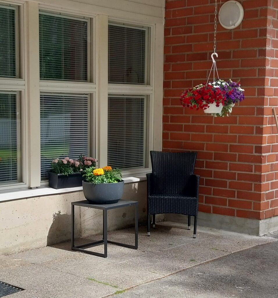 Yksikön piha, jossa pöytä, tuoli ja kukka-asetelmat