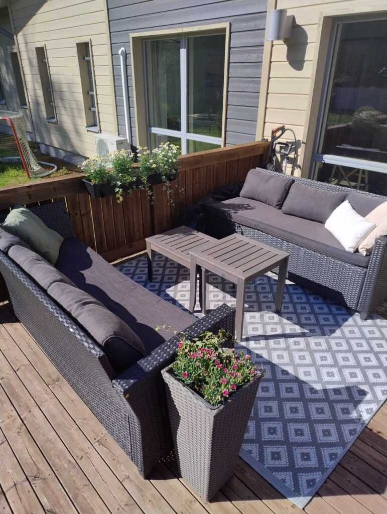 Familar Ylöjärvi: ulkoterassi kesällä. Viihtyisällä ja aurinkoisella terassilla on kaksi sohvaa ja sohvapöytä niiden välissä.