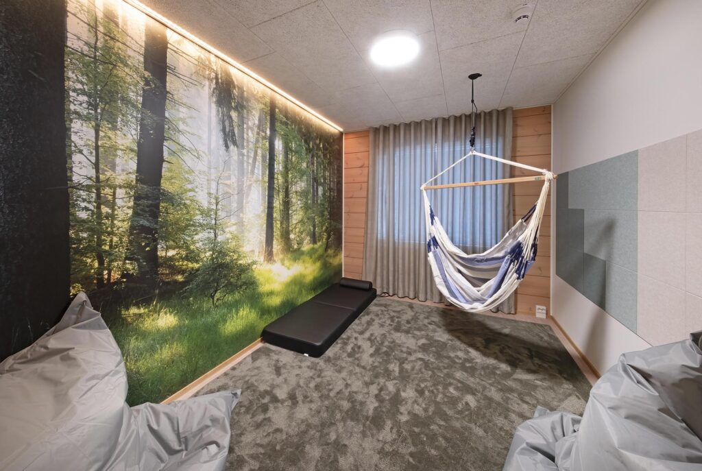 Aistihuone, jossa riippukeinu ja metsäinen sisustustapetti