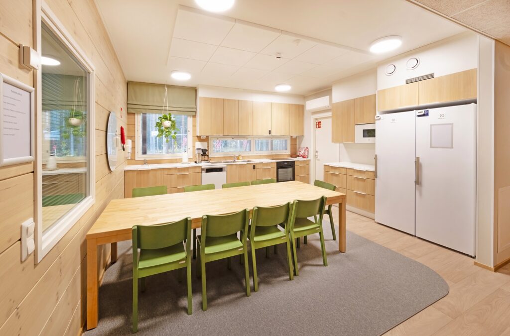Keittiötilat lastensuojeluyksikössä, pitkä pöytä, tuoleja