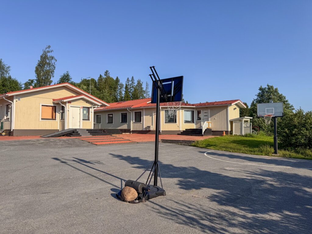 Nuorisokoti Nummelan yksikkö ulkoa. Keltainen rakennus ja koriskenttä.