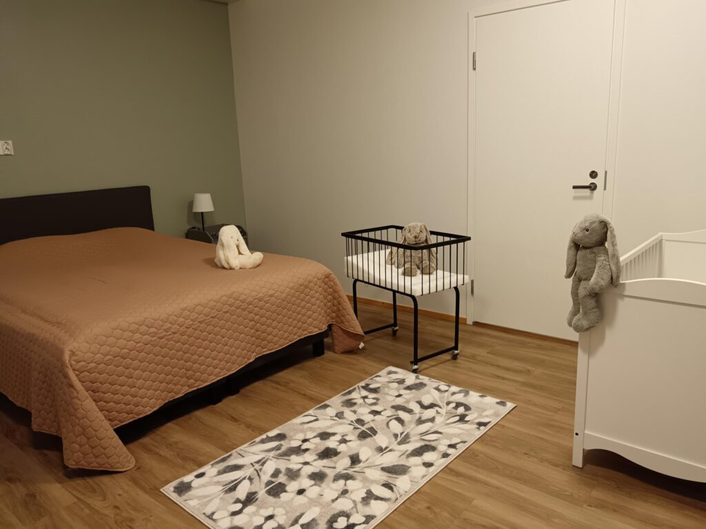 Huone jossa parisänky ja vauvan sänky.