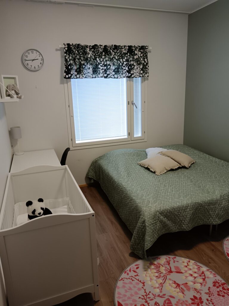 Sisustettu huone, jossa pari sänky ja pinnasänky.