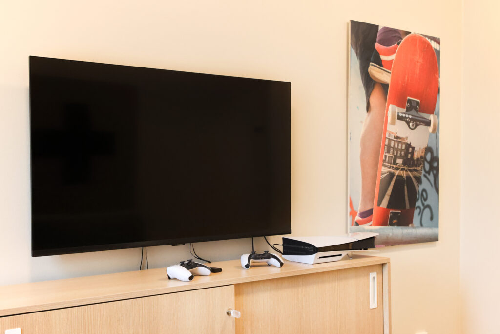 Televisio ja peliohjaimet lipaston päällä.