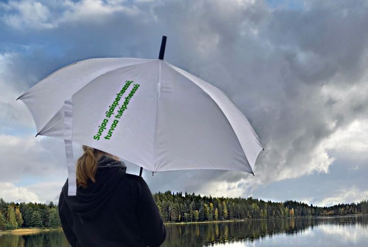 Sateenvarjo ja tyttö laiturilla järvimaisemassa.